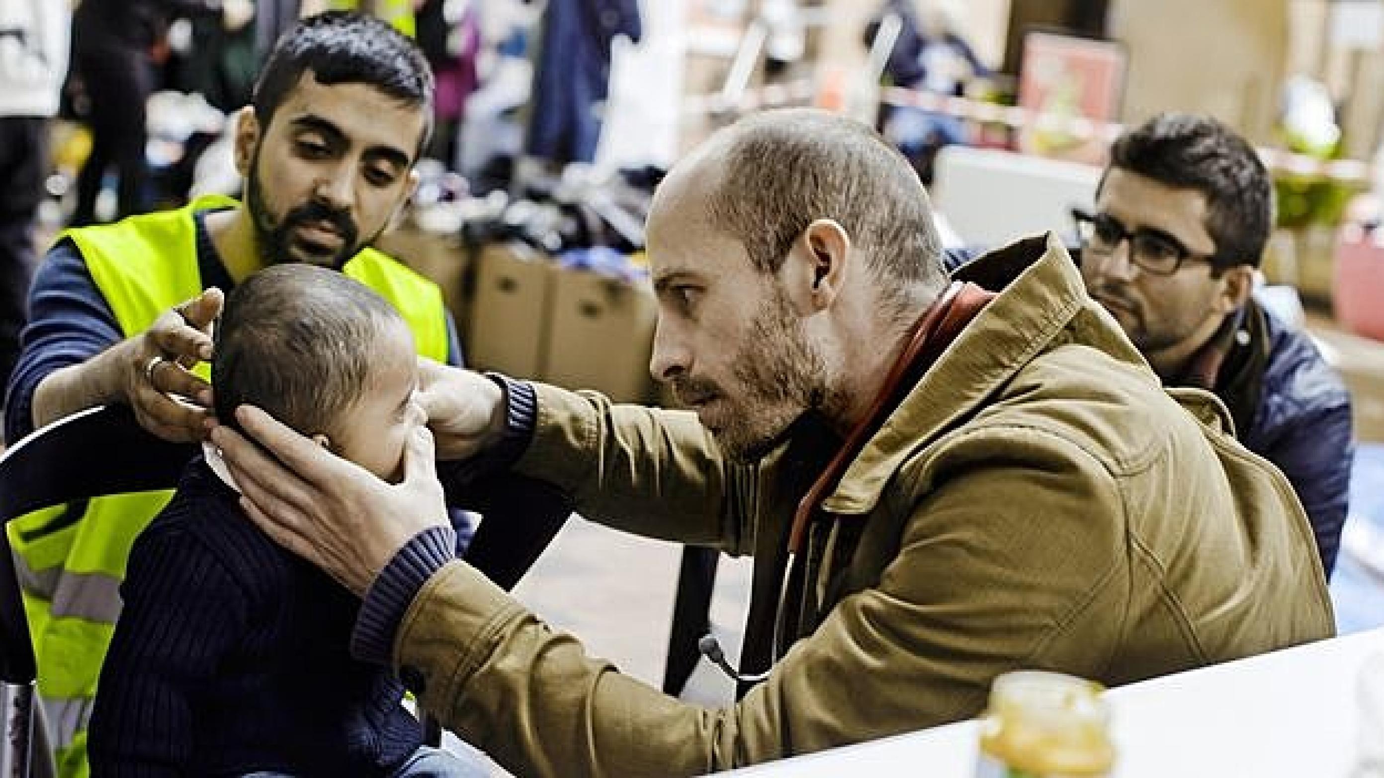 Læge Johan Stender undersøger et barn i det afspærrede område på Hovedbanegården. Her er både lægekonsultation og doneret mad og tøj til flygtningene. Foto: Claus Boesen