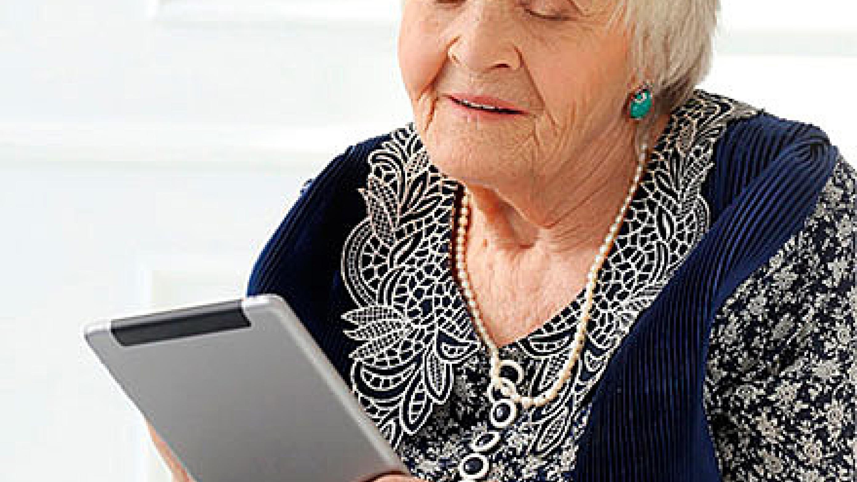 En ældre patient, der udfylder et patient reported outcome measures-skema på en tablet i ambulatoriets venteværelse.