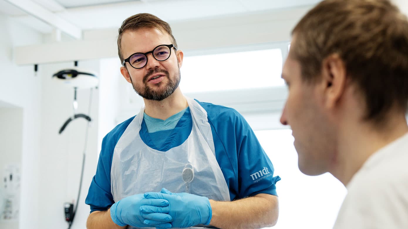 Rehne Lessmann Hansen taler med Andriy, en af de ukrainske krigstraumepatienter, der bliver behandlet på AUH for voldsomme skader og infektioner. Foto: Martin Dam Kristensen