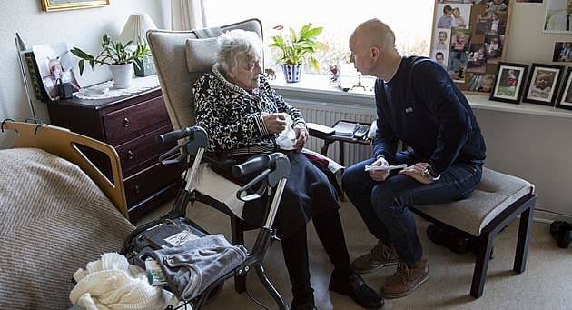 "Det er vigtigt, at du bliver ved med at træne dine ben, så du selv kan rejse dig op", forklarer praktiserende læge Rasmus Dahl-Larsen en beboer på det plejehjem, hvor han kommer fast. Foto: Heidi Lundsgaard.