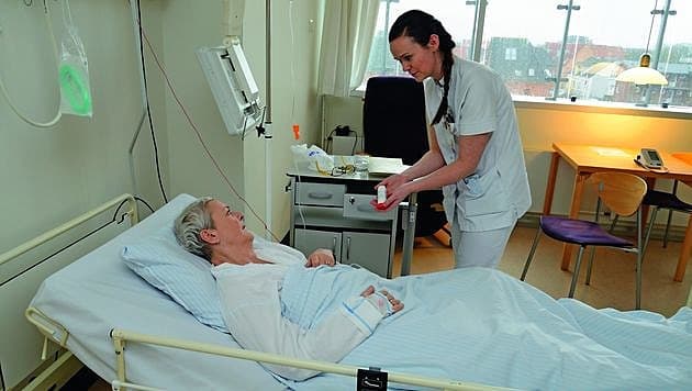 Sygeplejerske Sara Eiersted McNally under stuegang hos patient Mona Nyholm Aabenhuus. Her snakkes der også medicin, og den er lige ved hånden – nemlig i skuffen i sengebordet. Foto: Jørgen Ploug.