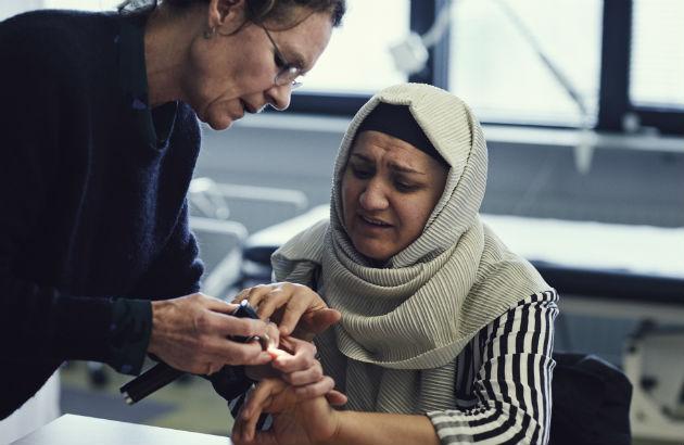 Lise Dyhr undersøger en patient, der er mødt op uden tolk. Hun taler kun lidt dansk og må assisteres af en pårørende, der er med på telefonen. Foto: Ulrik Jantzen.