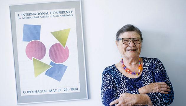 Jette Kristiansen med logoet fra verdenskonferencen i 1990 og det nyoprettede videnskabelige selskab ”The international Society of Non-Antibiotics, skabt af billedhugger Mogens Møller. Det har titlen: Kunst, former og farver forenet til videnskab