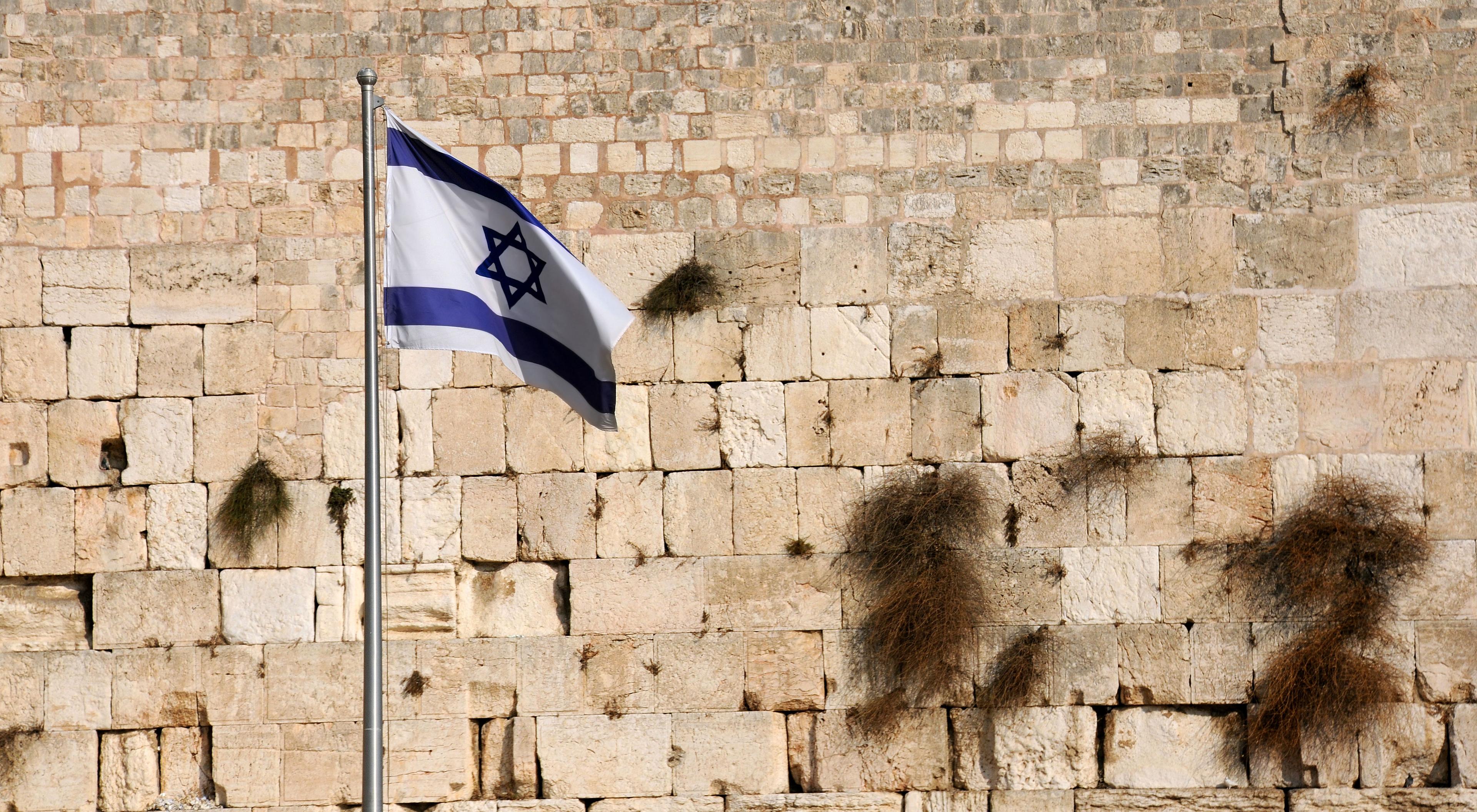 Staten Israels flag foran en bymur i Jerusalem. Foto: Colourbox.