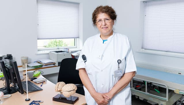 På Nasrin Asgaris skrivebord står figurer af hjerner og øjne. Opslagstavlen er fuld af gruppebilleder, julekort, plancher, portrætter fra forskningssamarbejder over hele verden. Foto: Claus Bech