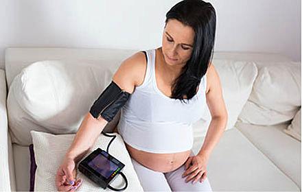 Gravid kvinde måler blodtryk.