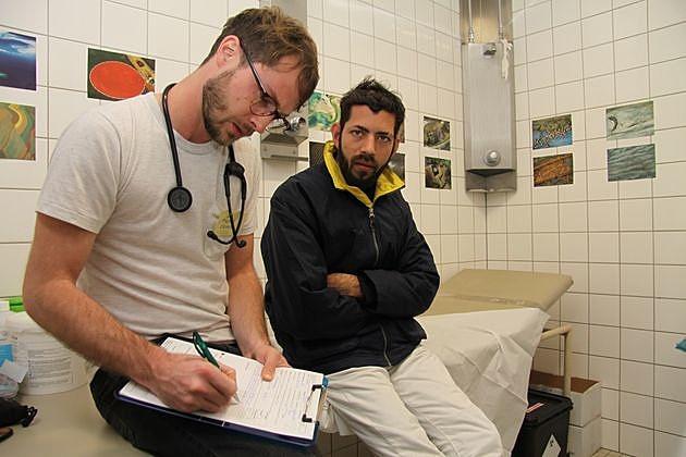 Thomas Cronen arbejder som læge i en interimistisk klinik i et omklædningsrummet på et berlinsk sportsanlæg. Her bor flere tusind flygtninge under tvivlsomme hygiejniske forhold.