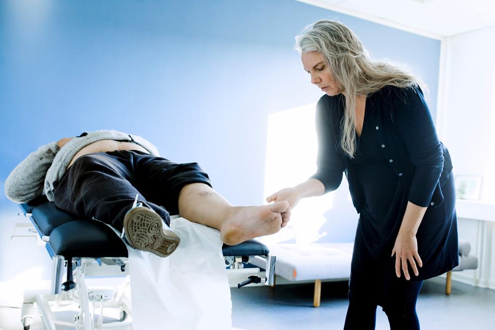 Praktiserende læge, Berit Enggaard Kaae undersøger Jørgens ben, som driller, efter at han ved et uheld kom til at skære sig med en kniv. Jørgen er multisyg og har både KOL, højt blodtryk, søvnbesvær, er tyktarmsopereret, og har et større alkoholmisbrug i bagagen. Foto: Claus Boesen