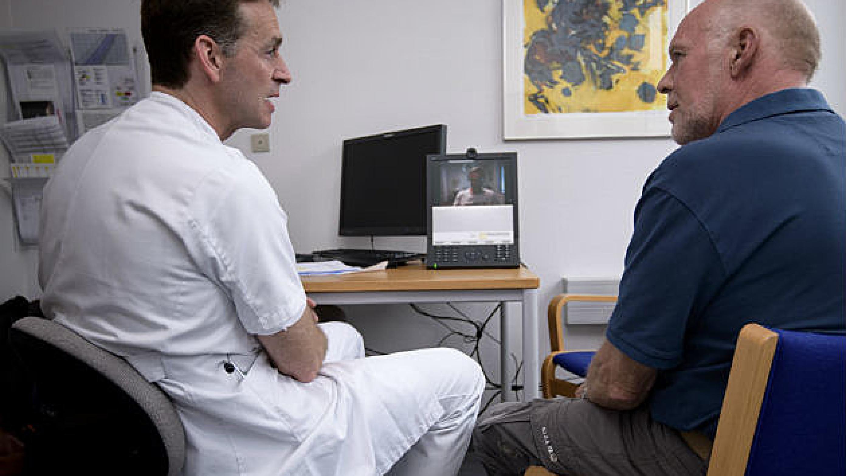 Lars Henrik Jensen, onkolog og Kim Häuser, kræftpatient, taler med Niels Abildtrup. Han er Kim Häusers egen læge og med på en videoskærm. Foto: Peter Palle Skov. 