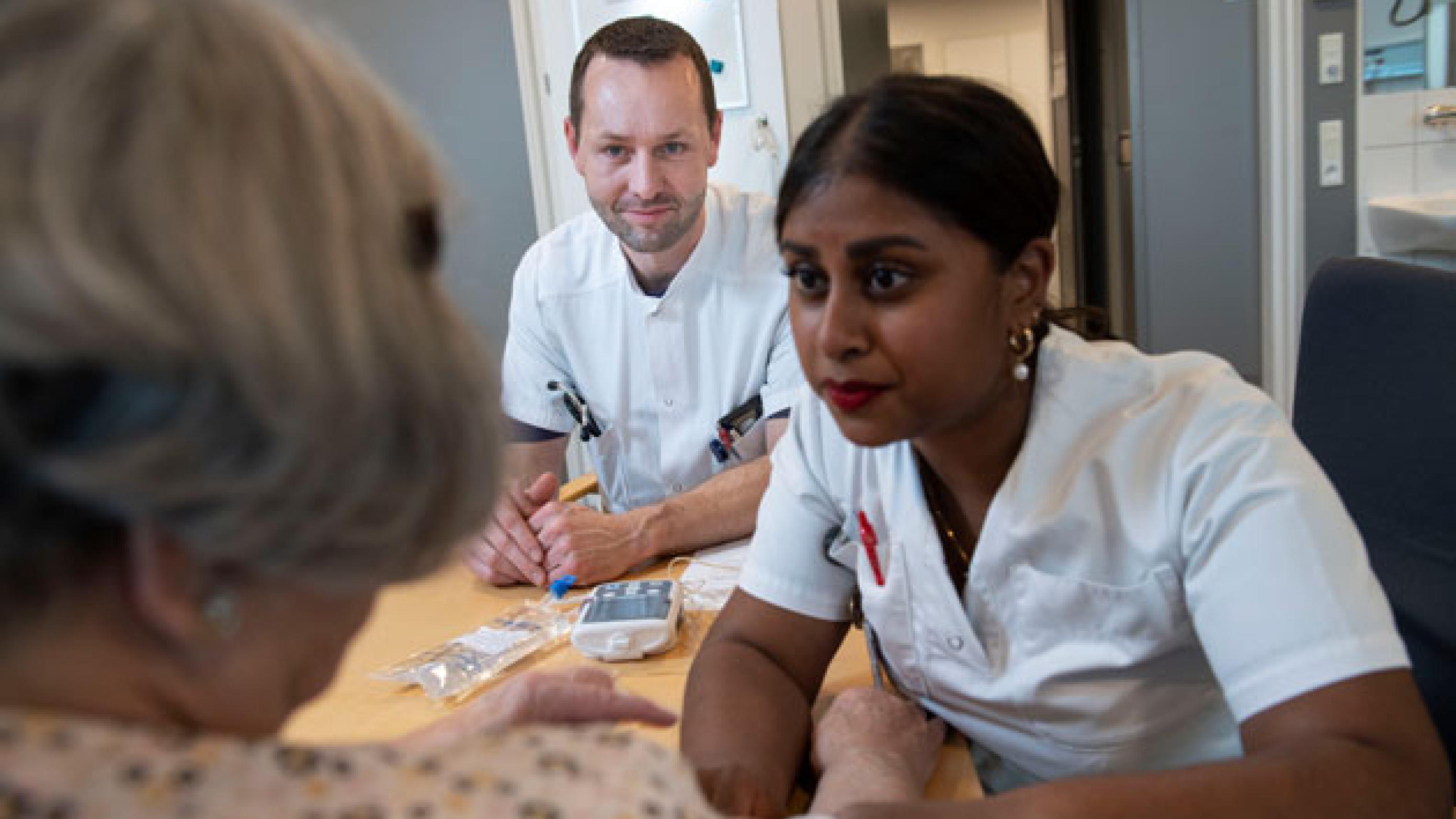 Jesper Smit er læge på Infektionsmedicinsk Afdeling. Her sidder han sammen med sygeplejerske Gousiga Yogarajan og en patient. Foto: Lars Horn/Baghuset